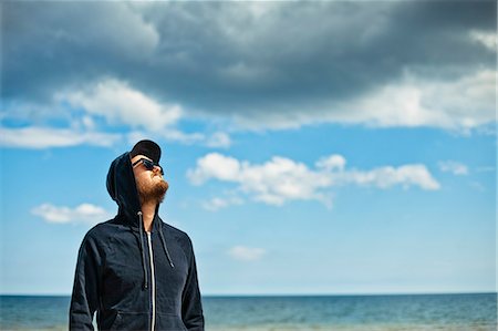 simsearch:6126-08644036,k - Sweden, Oland, Portrait of man in hooded shirt looking at sky Stock Photo - Premium Royalty-Free, Code: 6126-08642811