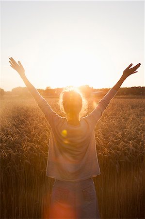 simsearch:6126-08636086,k - Sweden, Skane, Rear view of woman raising arms in field at sunset Foto de stock - Royalty Free Premium, Número: 6126-08642934