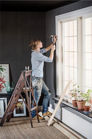 escalera de mano - Sweden, Mid-adult woman hammering nail in living room Foto de stock - Sin royalties Premium, Código: 6126-08643172