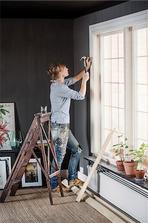 pictures of people moving house - Sweden, Mid-adult woman hammering nail in living room Stock Photo - Premium Royalty-Free, Code: 6126-08643172