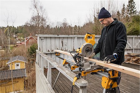 simsearch:6126-09103001,k - Sweden, Uppland, Rindo, Man cutting wood with circular saw Foto de stock - Sin royalties Premium, Código: 6126-08643195