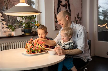 simsearch:6126-08635086,k - Sweden, Man and two boys (18-23 months, 4-5) decorating gingerbread house Foto de stock - Royalty Free Premium, Número: 6126-08643203