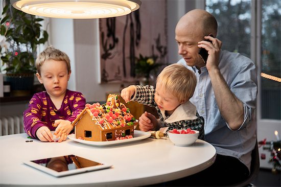 Sweden, Man and two boys (18-23 months, 4-5) decorating gingerbread house Stock Photo - Premium Royalty-Free, Image code: 6126-08643201