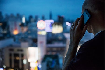 Japan, Tokyo, Shibuya, Man talking on phone and looking through window Stock Photo - Premium Royalty-Free, Code: 6126-08643218