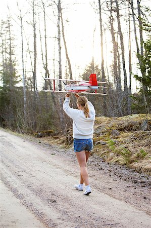 simsearch:6126-08643885,k - Sweden, Uppland, Lanna, Girl (12-13) carrying plane over head Foto de stock - Sin royalties Premium, Código: 6126-08643621