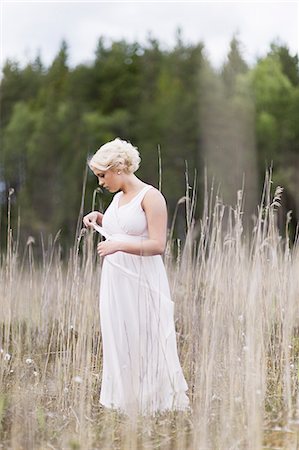simsearch:6126-08636185,k - Sweden, Vastmanland, Teenage girl (16-17) in white dress standing in meadow among dried plants Foto de stock - Sin royalties Premium, Código: 6126-08643990