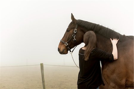 simsearch:6126-08635432,k - Sweden, Skane, Mid-adult woman with horse on dirt road in fog Fotografie stock - Premium Royalty-Free, Codice: 6126-08643923