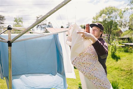 dry the bed sheets - Sweden, Vasterbotten, Young man hanging laundry Photographie de stock - Premium Libres de Droits, Code: 6126-08644058