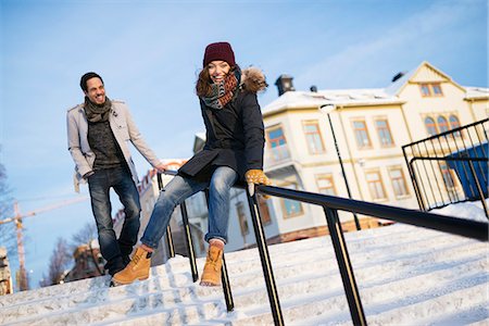 simsearch:6126-08644046,k - Sweden, Vasterbotten, Umea, Man watching young woman sliding on railing Stock Photo - Premium Royalty-Free, Code: 6126-08644064