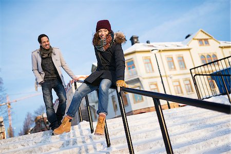 snow foot prints - Sweden, Vasterbotten, Umea, Man watching young woman sliding on railing Stock Photo - Premium Royalty-Free, Code: 6126-08644064