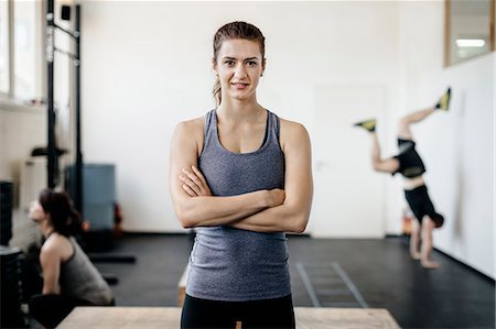 redhead young woman portrait - Germany, Portrait of young woman standing in gym with arms crossed Stock Photo - Premium Royalty-Free, Code: 6126-08644271
