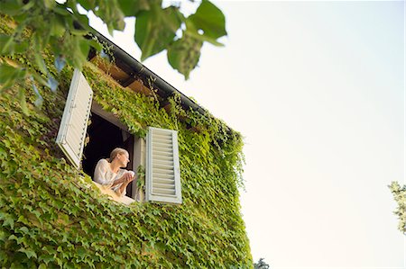 simsearch:6126-08644371,k - Italy, Tuscany, Dicomano, Woman looking out from window of overgrown house Photographie de stock - Premium Libres de Droits, Code: 6126-08644371