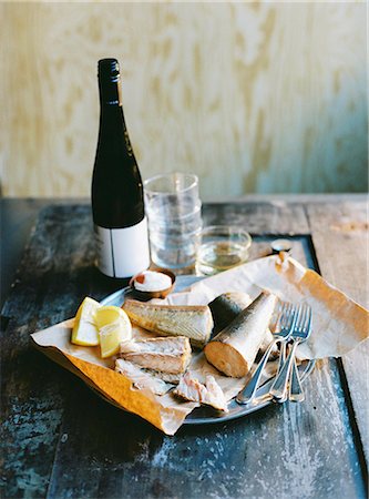 Sweden, Smoked fish, lemon, cutlery and bottle of wine on wooden table Stockbilder - Premium RF Lizenzfrei, Bildnummer: 6126-08644325