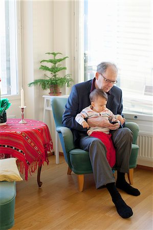 finnish ethnicity (male) - Finland, Senior man sitting in armchair and holding grandson (18-23 months) on laps Stock Photo - Premium Royalty-Free, Code: 6126-08644697