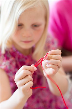 Finland, Girl (8-9) tying red string Stock Photo - Premium Royalty-Free, Code: 6126-08644776