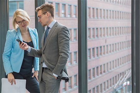 photos with women 19 years - Finland, Helsinki, Business people looking on mobile phone by window Stock Photo - Premium Royalty-Free, Code: 6126-08644903