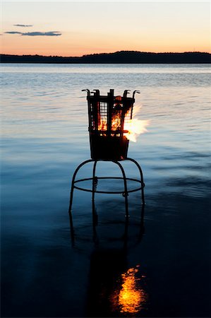 Sweden, Stockholm, Sodermanland, Dalaro, Brazier on lake at sunset Stock Photo - Premium Royalty-Free, Code: 6126-08658942