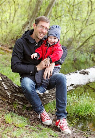 Sweden, Bohuslan, Tjorn, Father and son (2-3) sitting on branch Stock Photo - Premium Royalty-Free, Code: 6126-08658990