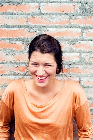 simsearch:6126-08659298,k - Sweden, Uppland, Danderyd, Smiling young woman against brick wall Stock Photo - Premium Royalty-Free, Code: 6126-08659142