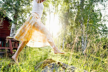 simsearch:6126-08635820,k - Sweden, Dalarna, Svardsjo, Young woman jumping in grass in backyard Fotografie stock - Premium Royalty-Free, Codice: 6126-08659144