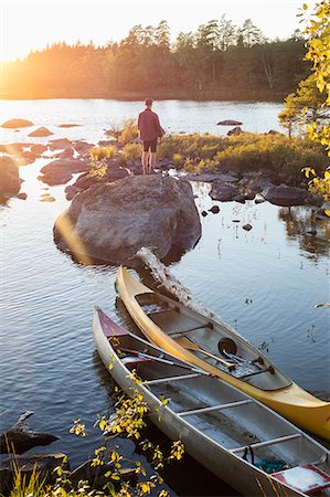 Sweden, Skane, Filkesjon, Man standing on rock at sunset Stock Photo - Premium Royalty-Free, Code: 6126-08659168