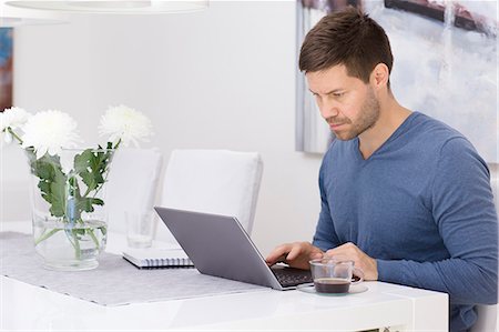 flowers on desk - Sweden, Mid adult man using laptop Stock Photo - Premium Royalty-Free, Code: 6126-08659279