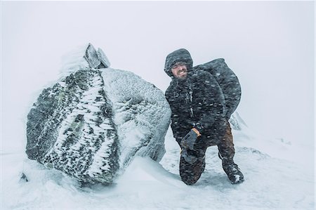 Sweden, Sylama, Jamtland, Young backpacker kneeling next to rock during snow blizzard Photographie de stock - Premium Libres de Droits, Code: 6126-08659464