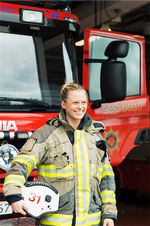 Sweden, Smiling female firefighter by fire engine Photographie de stock - Premium Libres de Droits, Code: 6126-08635153