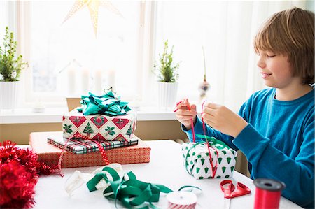 Boy (10-11) wrapping Christmas presents Stock Photo - Premium Royalty-Free, Code: 6126-08635196