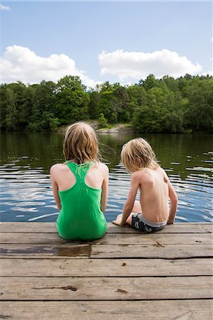 Sweden, Stockholm, Nacka, Sicklasjon, Lake Sickla, Rear view of children (6-7, 10-11) sitting on wooden jetty Stock Photo - Premium Royalty-Free, Code: 6126-08635137