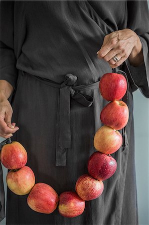 simsearch:6102-07282667,k - Sweden, Woman in grey dress standing holding apples tied up together Stock Photo - Premium Royalty-Free, Code: 6126-08635358