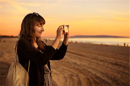 simsearch:6126-08635314,k - USA, California, Los Angeles, Santa Monica, Mid adult woman photographing at sunset Stock Photo - Premium Royalty-Free, Code: 6126-08635315