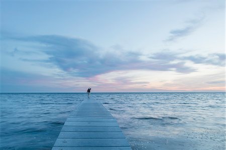 Sweden, Oland, Vasterstadsviken, Woman standing on pier at seaside Stock Photo - Premium Royalty-Free, Code: 6126-08635598