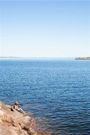 simsearch:633-05401482,k - Sweden, Uppland, Runmaro, Barrskar, Boy (6-7) sitting on rock by sea Photographie de stock - Premium Libres de Droits, Code: 6126-08635647