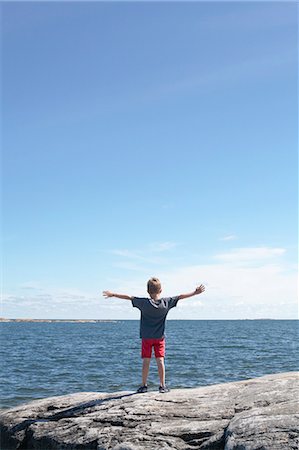 Sweden, Uppland, Runmaro, Barrskar, Boy (6-7) standing on seaside and looking at view Stock Photo - Premium Royalty-Free, Code: 6126-08635648