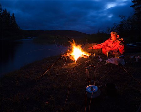 simsearch:6126-08644314,k - Sweden, Vastmanland, Svartalven, Man by bonfire on riverbank Stock Photo - Premium Royalty-Free, Code: 6126-08635817