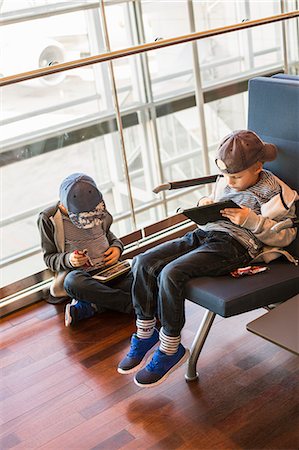 Sweden, Uppland, Two boys (6-7, 8-9) sitting and playing with tablets at waiting area of Arlanda Airport Stock Photo - Premium Royalty-Free, Code: 6126-08635942
