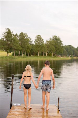 ethnic preteens swimwear girls - Sweden, Smaland, Braarpasjon, Girl (10-11) and boy (12-13) standing on edge of jetty Photographie de stock - Premium Libres de Droits, Code: 6126-08636055