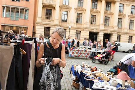 stand - Sweden, Stockholm, Normalm, Blasieholmstorg, Portrait of mature woman choosing dress at flea market Foto de stock - Sin royalties Premium, Código: 6126-08636091