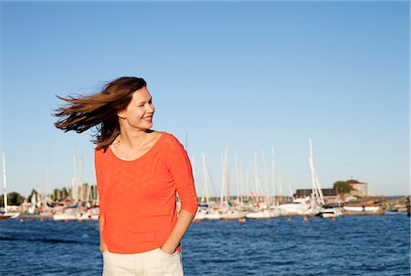 simsearch:6126-08635314,k - Finland, Uusimaa, Helsinki, Kaivopuisto, Portrait of smiling young woman with sea in background Stock Photo - Premium Royalty-Free, Code: 6126-08636494
