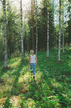 Finland, Mellersta Finland, Jyvaskyla, Saakoski, Woman walking across forest glade Photographie de stock - Premium Libres de Droits, Code: 6126-08636693