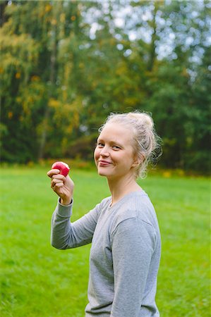 finland food - Finland, Uusimaa, Sipoo, Woman eating apple outdoors Stock Photo - Premium Royalty-Free, Code: 6126-08636726