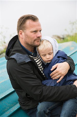 simsearch:6126-08636742,k - Sweden, Gotland. Mature man sitting on boat turned upside down and holding boy (6-7) Stock Photo - Premium Royalty-Free, Code: 6126-08781173