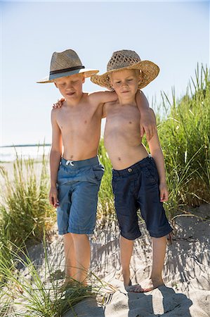 sin camisa - Sweden, Gotland, Shirtless boys (6-7, 8-9) in straw hats standing on sand dune at seashore Foto de stock - Sin royalties Premium, Código: 6126-08781180