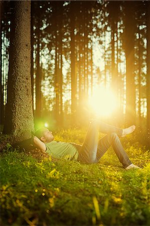 simsearch:6126-08636707,k - Finland, Heinola, Paijat-Hame, Man sleeping by tree in spruce forest Stock Photo - Premium Royalty-Free, Code: 6126-08781518