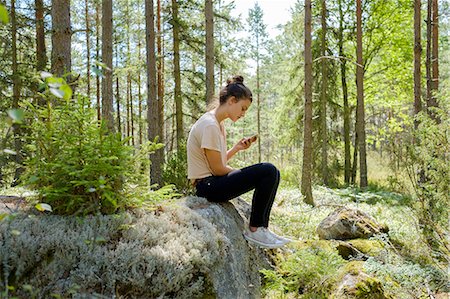 Girl sitting on rock in forest using smartphone Foto de stock - Sin royalties Premium, Código: 6126-09102644