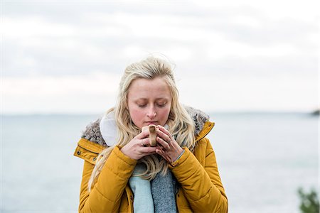 simsearch:6126-09104114,k - Young blonde woman drinking coffee by sea Photographie de stock - Premium Libres de Droits, Code: 6126-09102674