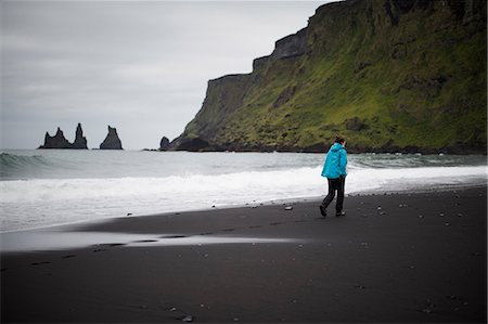 simsearch:6126-08636688,k - Hiker walking on black sand beach at feet of cliff in Iceland Photographie de stock - Premium Libres de Droits, Code: 6126-09102744