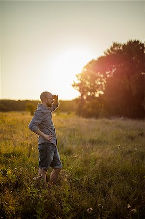 simsearch:6126-08644036,k - Man standing in grassy field at sunset Stock Photo - Premium Royalty-Free, Code: 6126-09102800