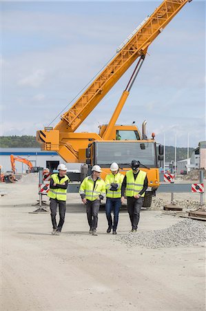 simsearch:6126-09104272,k - Construction workers walking with crane in background Stock Photo - Premium Royalty-Free, Code: 6126-09102979